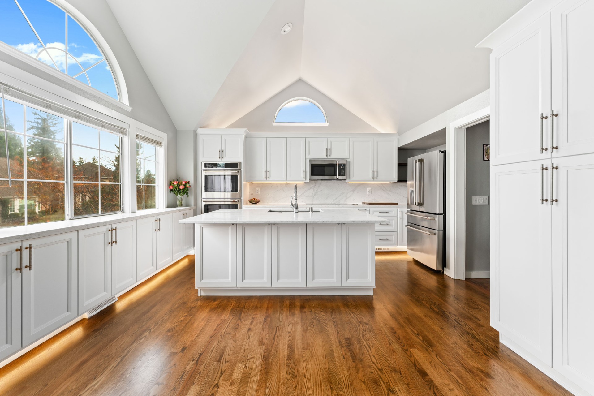 Bright modern white kitchen with marble island and hardwood floors
