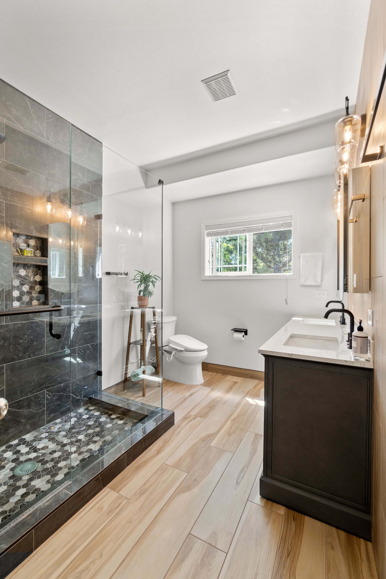 Modern remodeled bathroom with walk-in glass shower and dark vanity